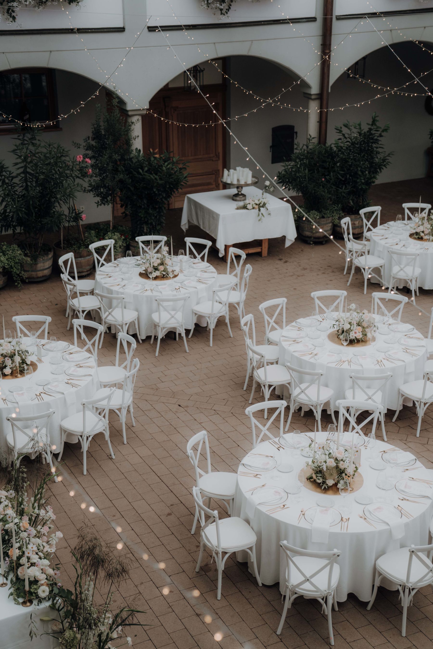 Gedeckter Innenhof mit weißer Bestuhlung und runden Tischen