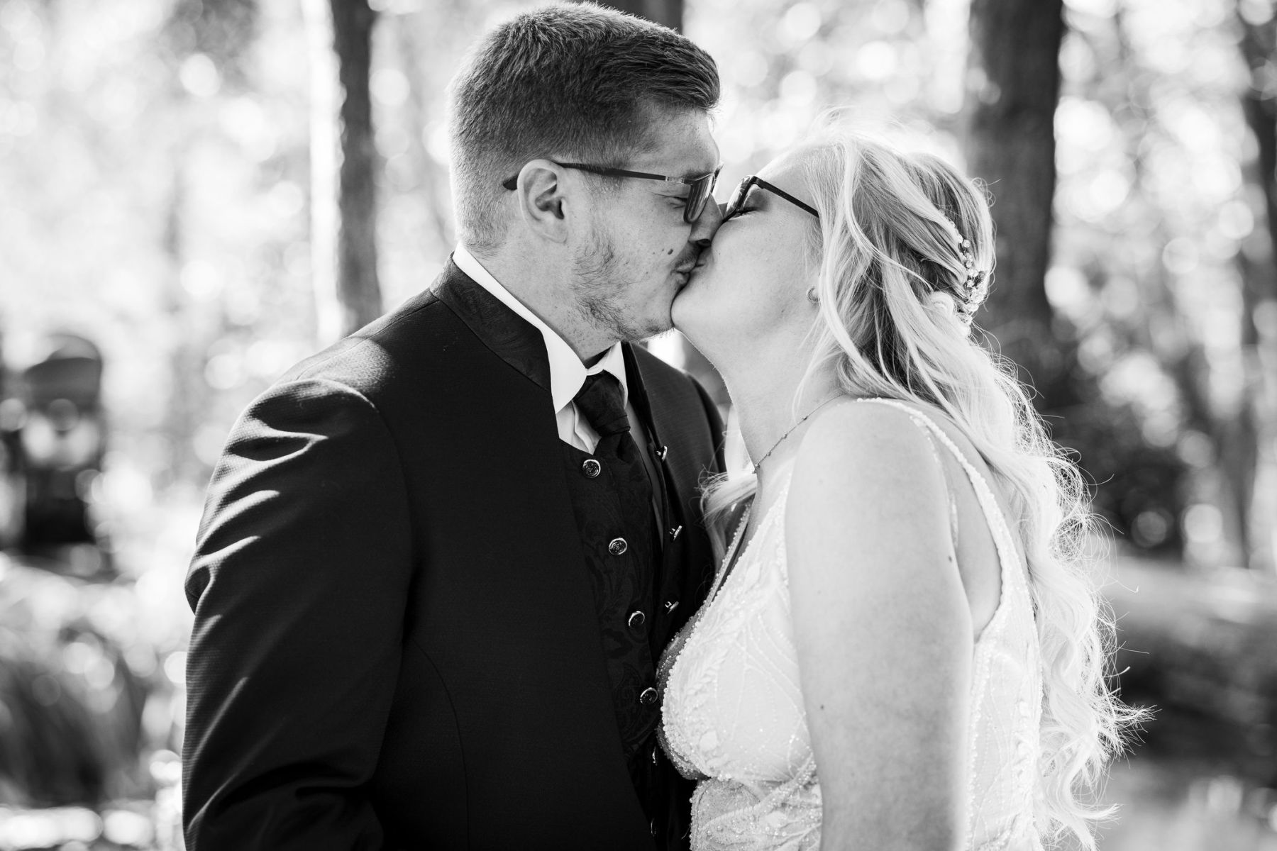 Hochzeitskuss auf der Liebesinsel am Vedahof – Braut neigt ihren Kopf liebevoll zum Bräutigam (Schwarz-Weiß)