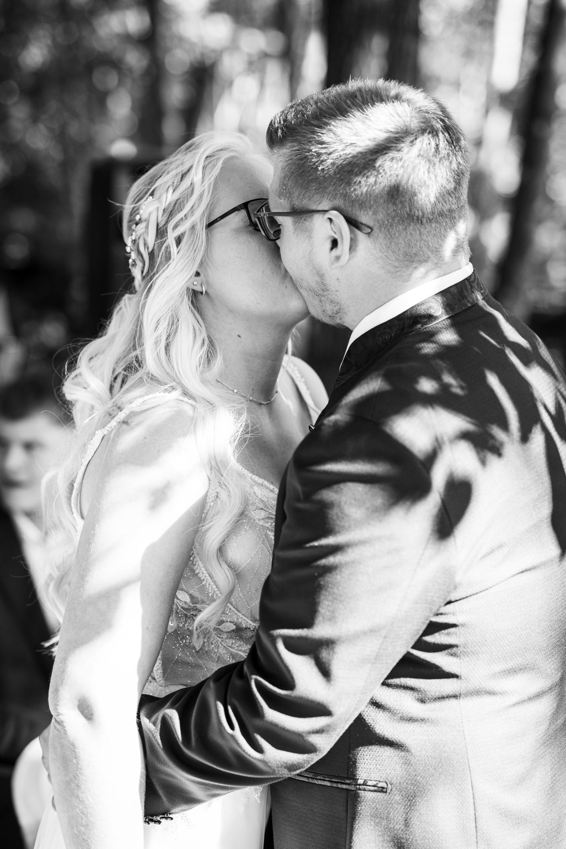 Hochzeitskuss auf der Liebesinsel am Vedahof – Bräutigam umarmt die Braut zärtlich (Schwarz-Weiß)