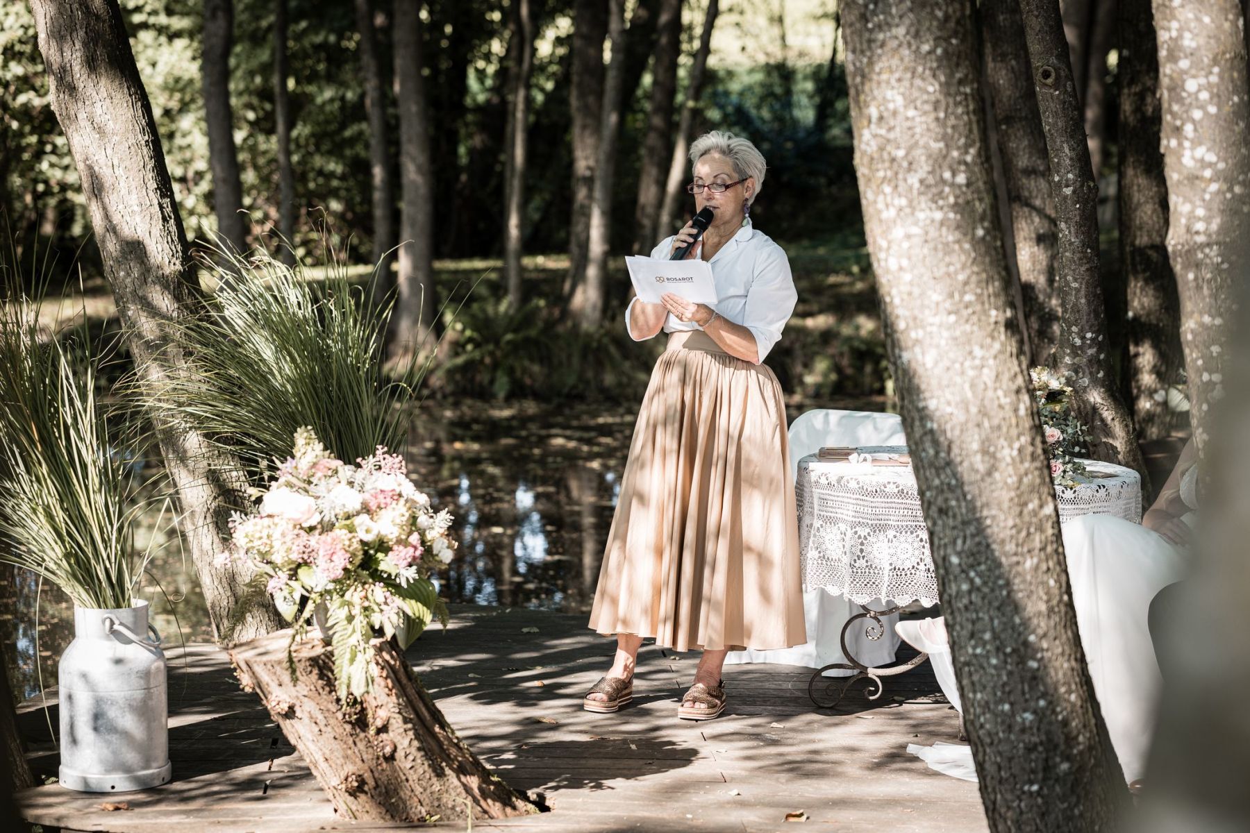 Traurednerin Rosarot auf der Liebesinsel am Vedahof spricht ins Mikrofon und richtet ihren Blick zu den Gästen.