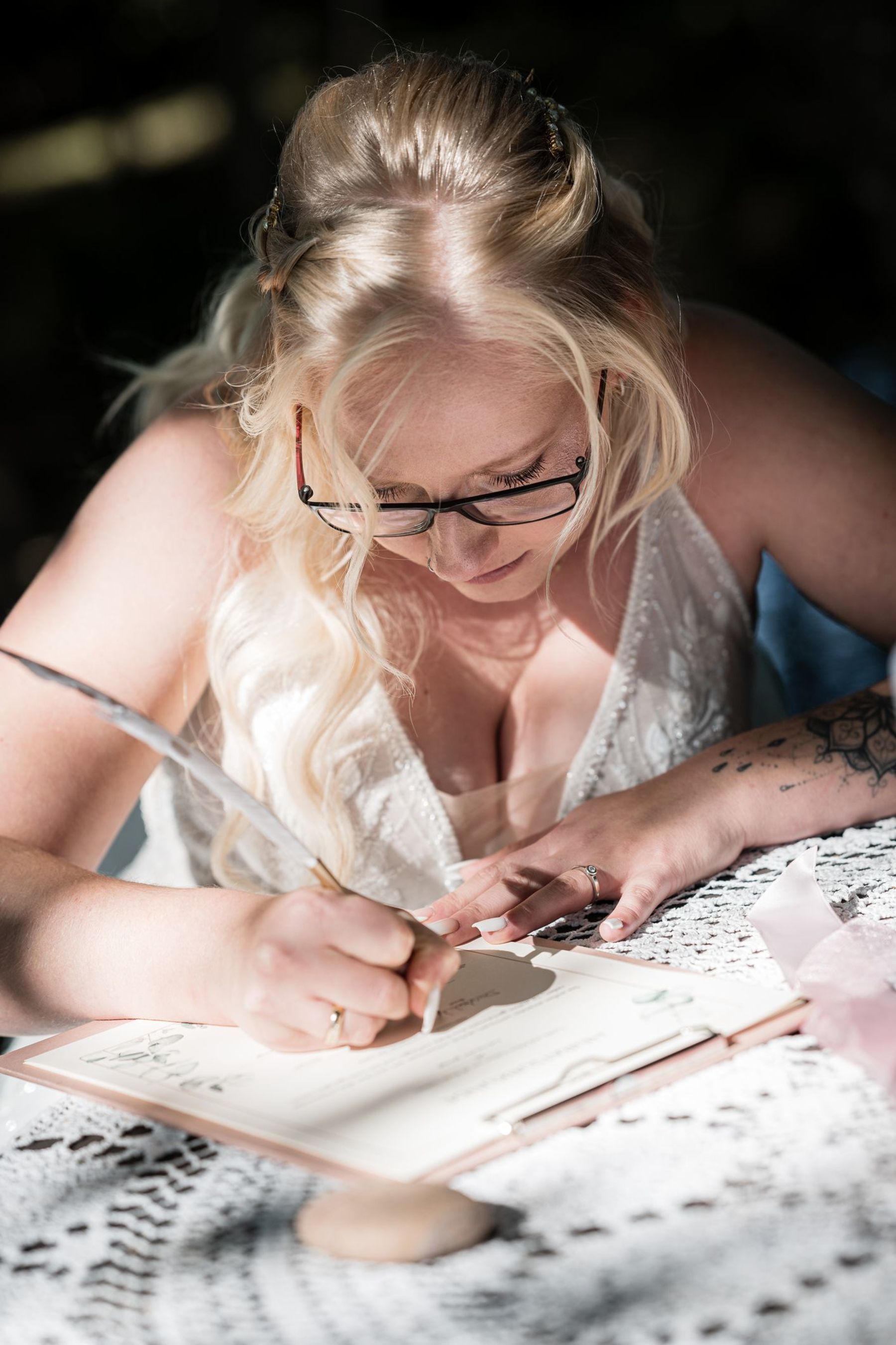 Close-up der Braut, die mit einem Federfüller die Eheurkunde auf der Liebesinsel am Vedahof unterschreibt.